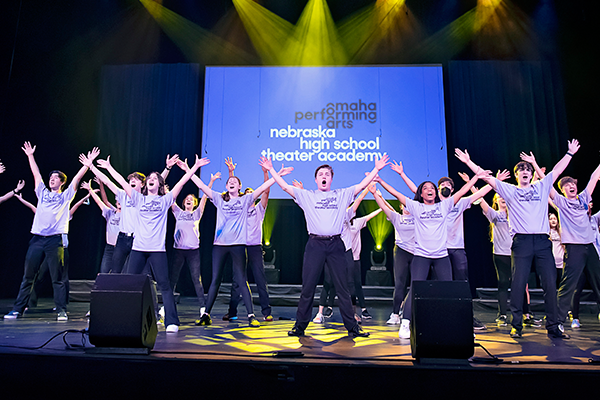 Students with arms up on stage at the 2023 NHSTA Showcase